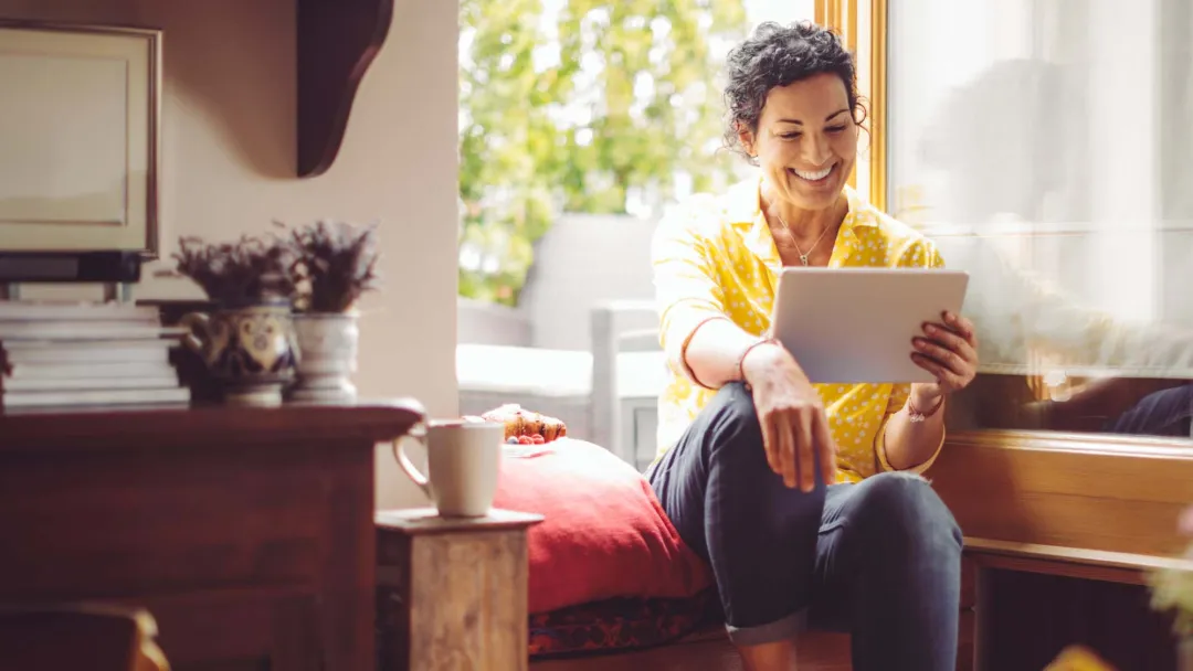 Middle-aged woman smiling at home with tablet