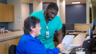 Two team members of AdventHealth Digestive Health Institute looking at a piece of paper and talking.