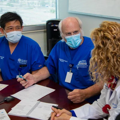 Dr. Sucandy, Dr. Rosemurgy speaking to Dr. Ross at a table