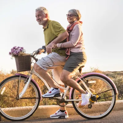 A couple rides a bike together.