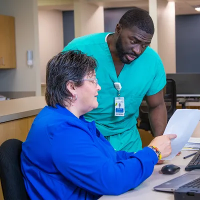 Two team members of AdventHealth Digestive Health Institute looking at a piece of paper and talking.
