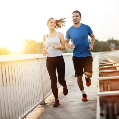 A couple runs by the side of a road.