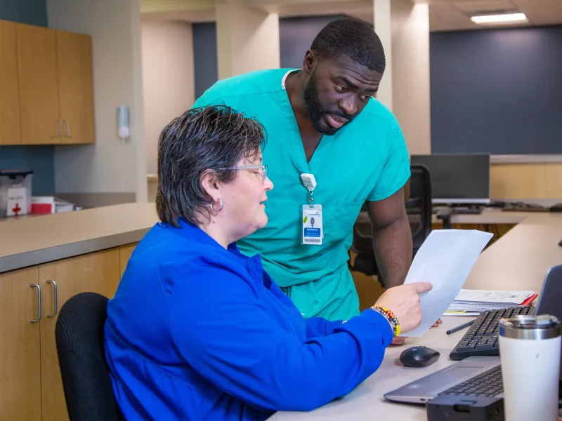 Two team members of AdventHealth Digestive Health Institute looking at a piece of paper and talking.