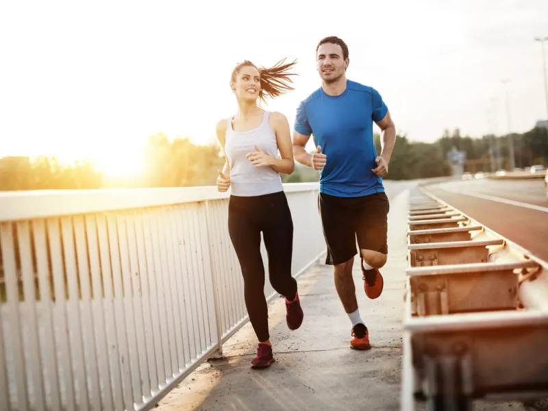 A couple runs by the side of a road.
