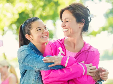 A daughter hugs her mother as they participate in a breast cancer walk.