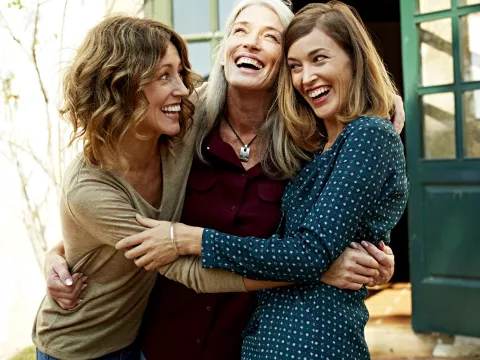 Three women celebrate their health by hugging each other.