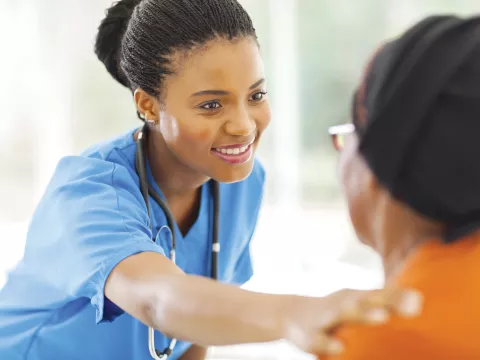 A nurse placing her hand on her patient's shoulder