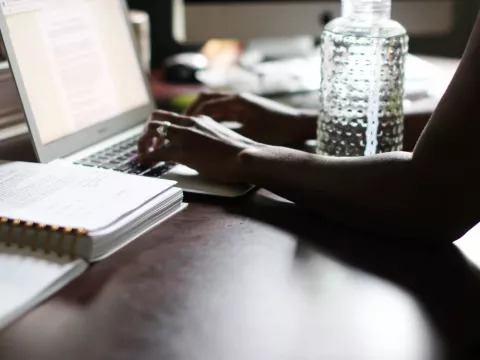 Woman typing on computer with water bottle