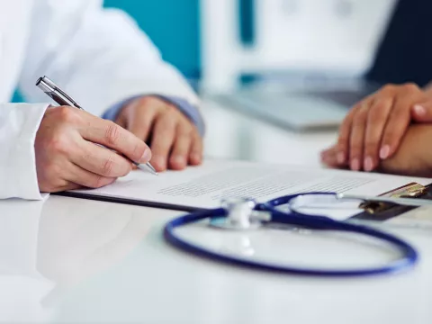 A doctor takes notes during a patient appointment.