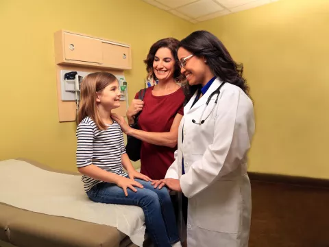 Doctor speaking with a mother and her child in an examination room
