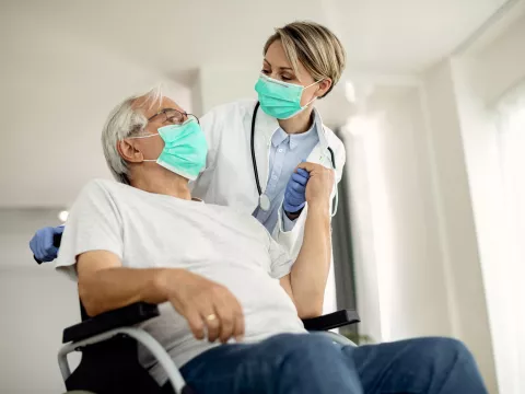 A doctor helping her senior patient on a wheelchair