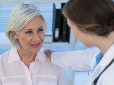 A woman talks with her doctor before an imaging test.
