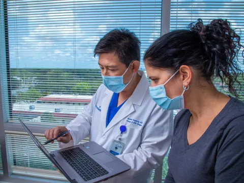 Iswanto Sucandy showing patient a something on a laptop.