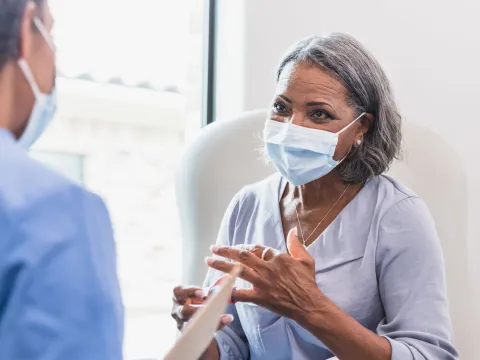 Masked Senior woman with physician