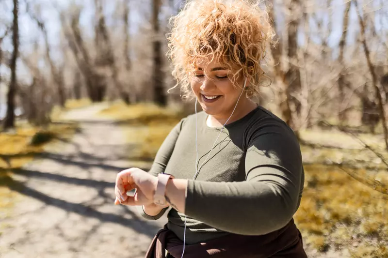 A Woman Checks Her Smart Watch While Going For a Run in the Park