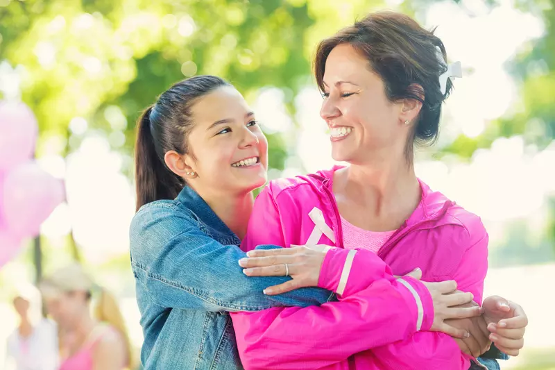 A daughter hugs her mother as they participate in a breast cancer walk.