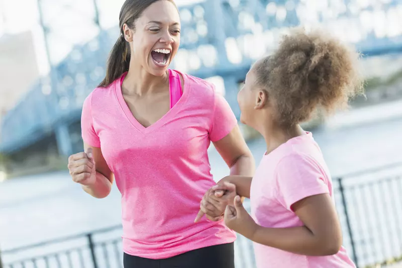 A mother and daughter are jogging together outside.