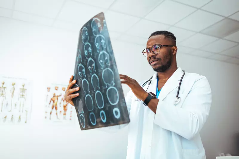 A male doctor holds up a sheet of brain scan images