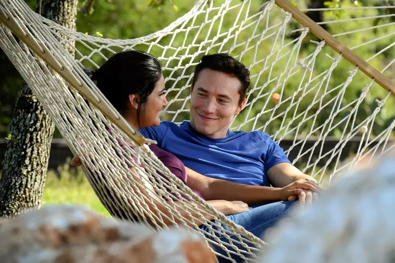 Couple sitting on a hammock outside.