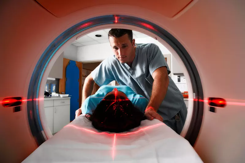 CT tech assisting patient while she gets a scan