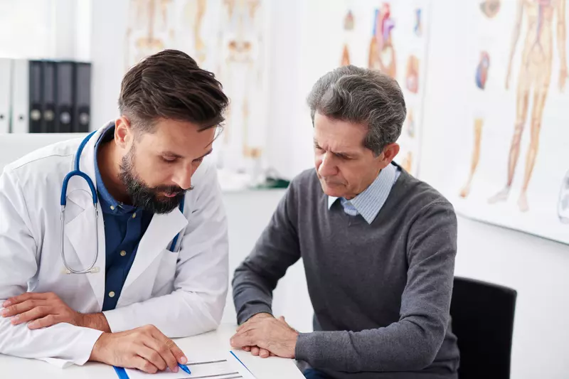 A doctor reviewing test results with a male patient at an appointment.