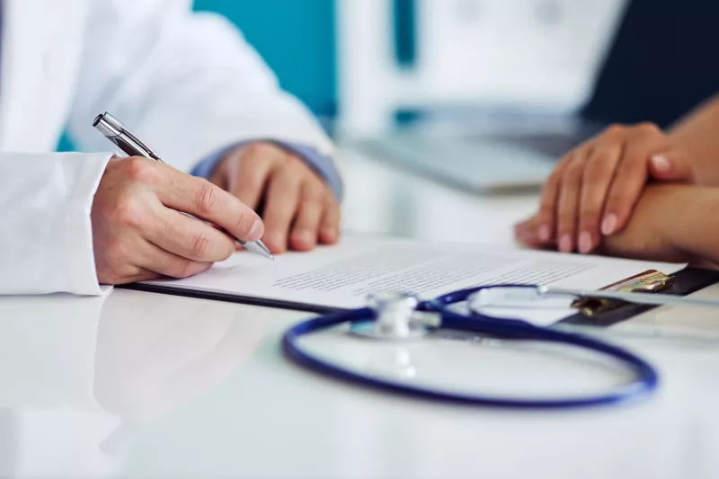 A doctor takes notes during a patient appointment.