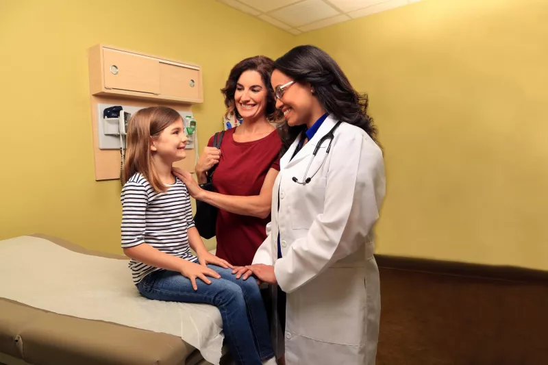 Doctor speaking with a mother and her child in an examination room