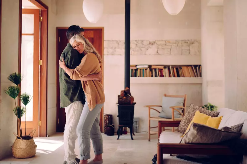 A mature man and woman embrace in their living room