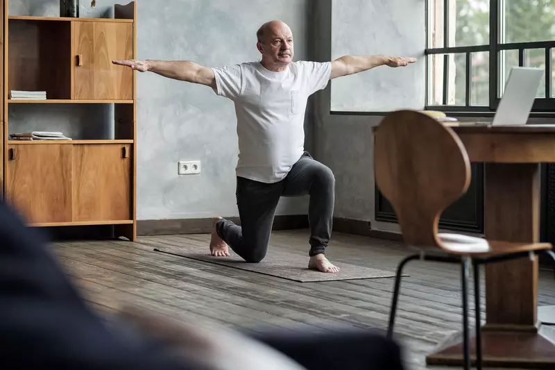 A older man stretching at home.