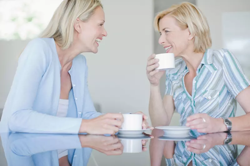 Two women chatting and drinking tea together.