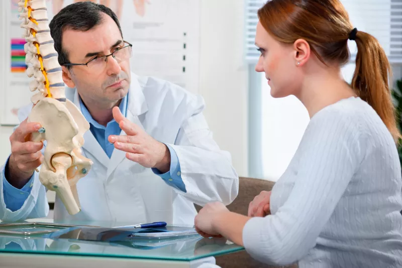 A woman discusses treatment options with her spine doctor.