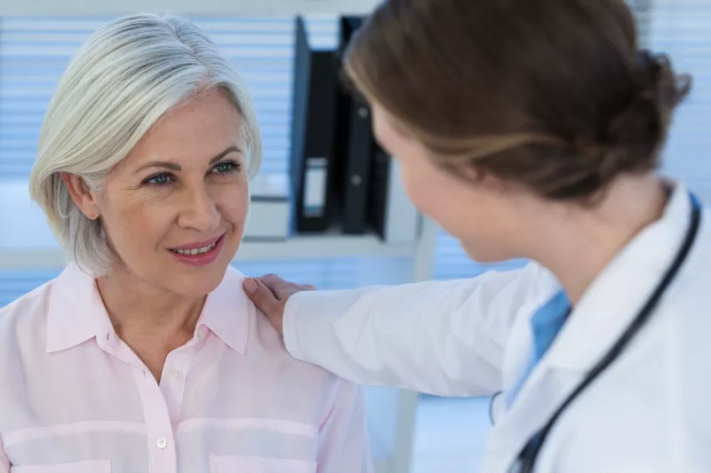 A woman talks with her doctor before an imaging test.