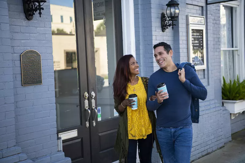 Hispanic Couple walking outdoors with coffee