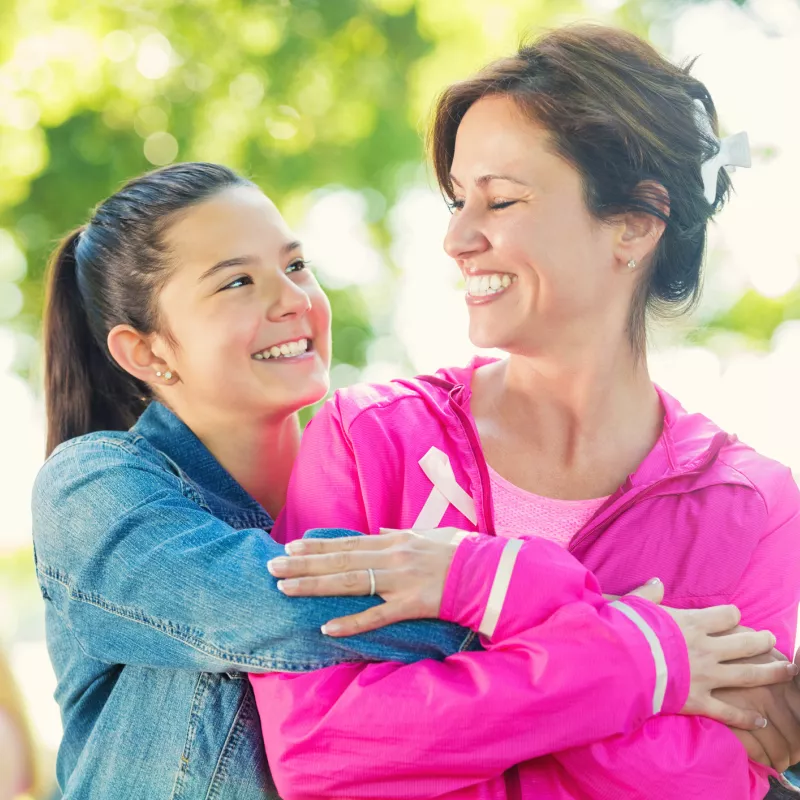 A daughter hugs her mother as they participate in a breast cancer walk.