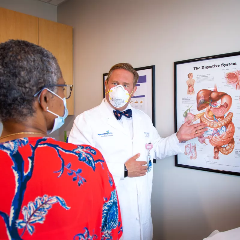 Allen Chudzinski showing patient diagram of digestive system while both are wearing masks at AdventHealth Digestive Institute Tampa.