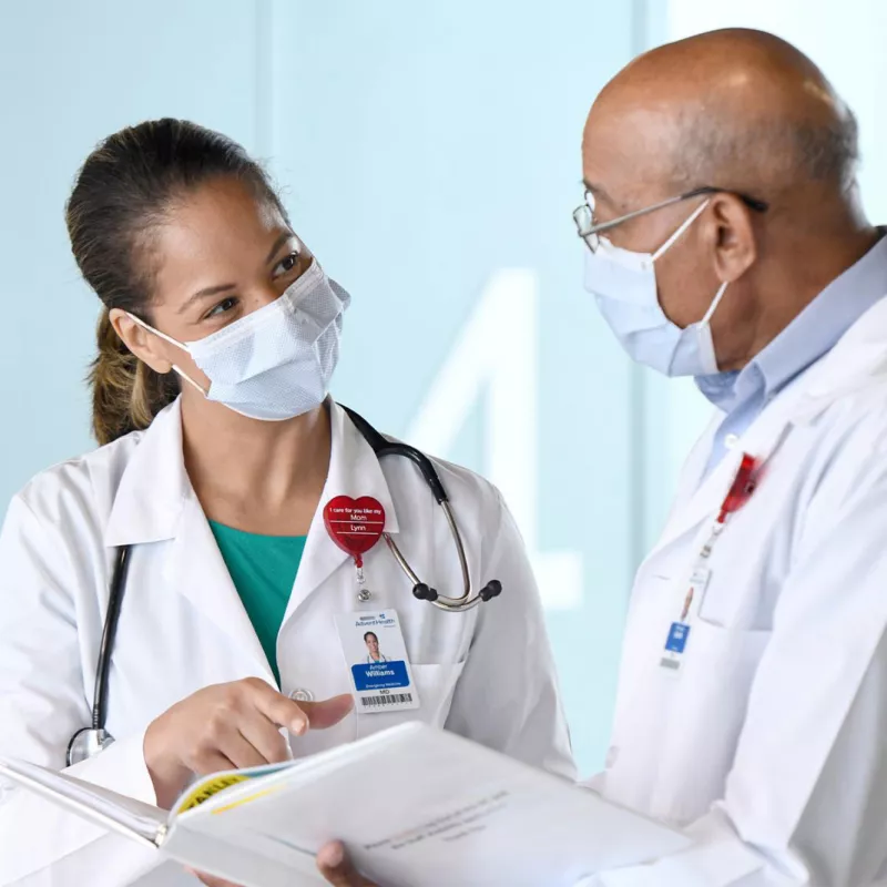 Two doctors talking while wearing masks.