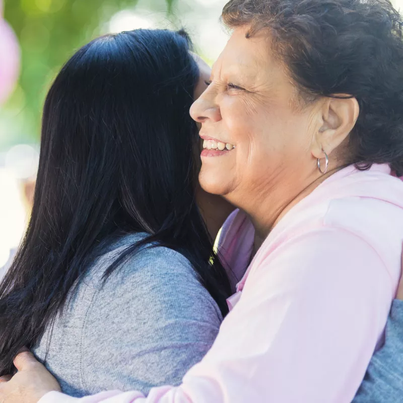 Two women hug at a breast cancer walk.