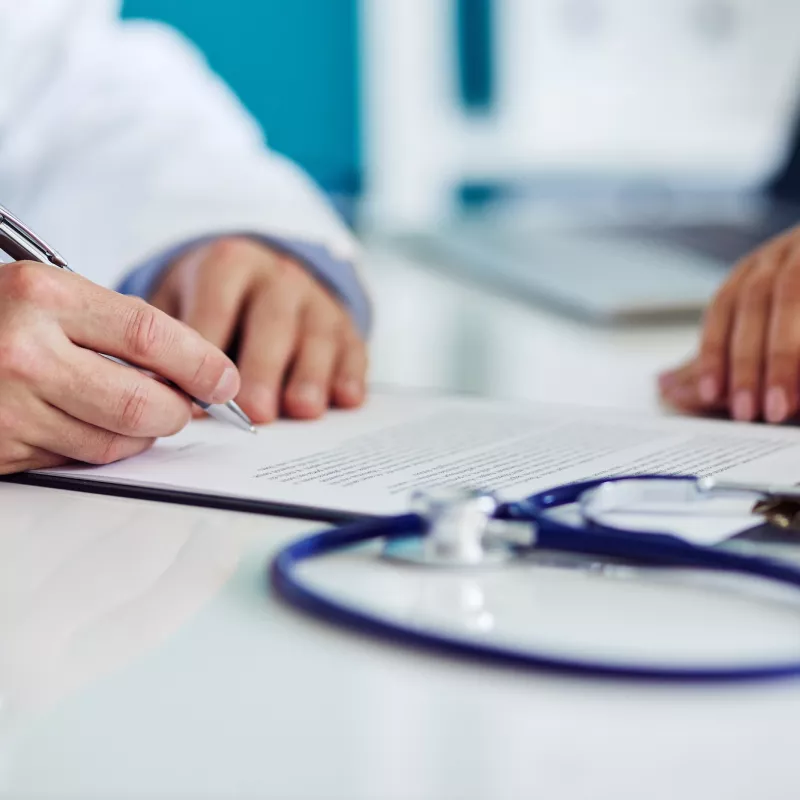 A doctor takes notes during a patient appointment.