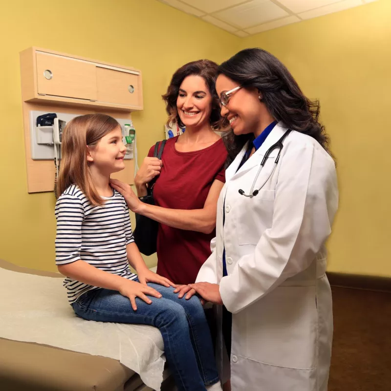 Doctor speaking with a mother and her child in an examination room