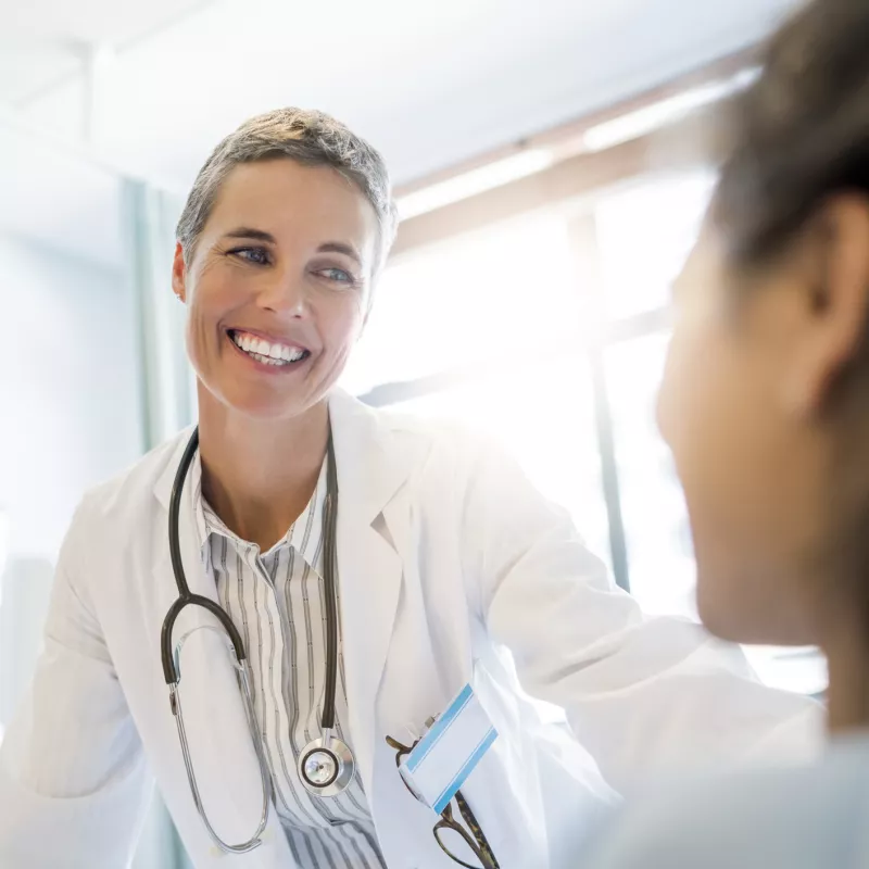 A doctor greets her patient at the bedside