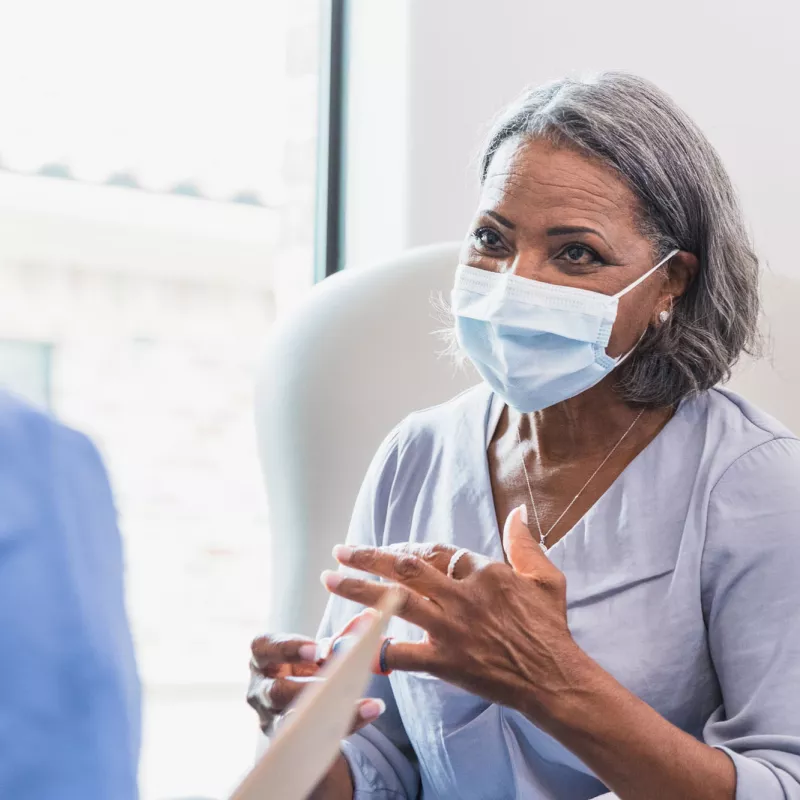 Masked Senior woman with physician